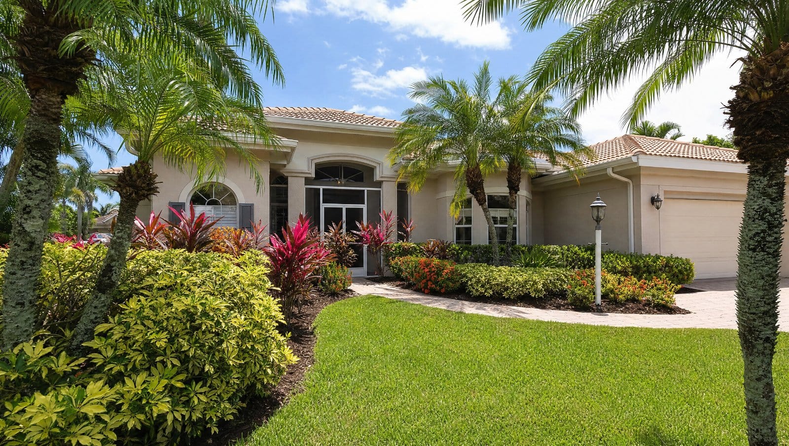 Beautifully landscaped Florida front yard with palms and colorful tropical plants