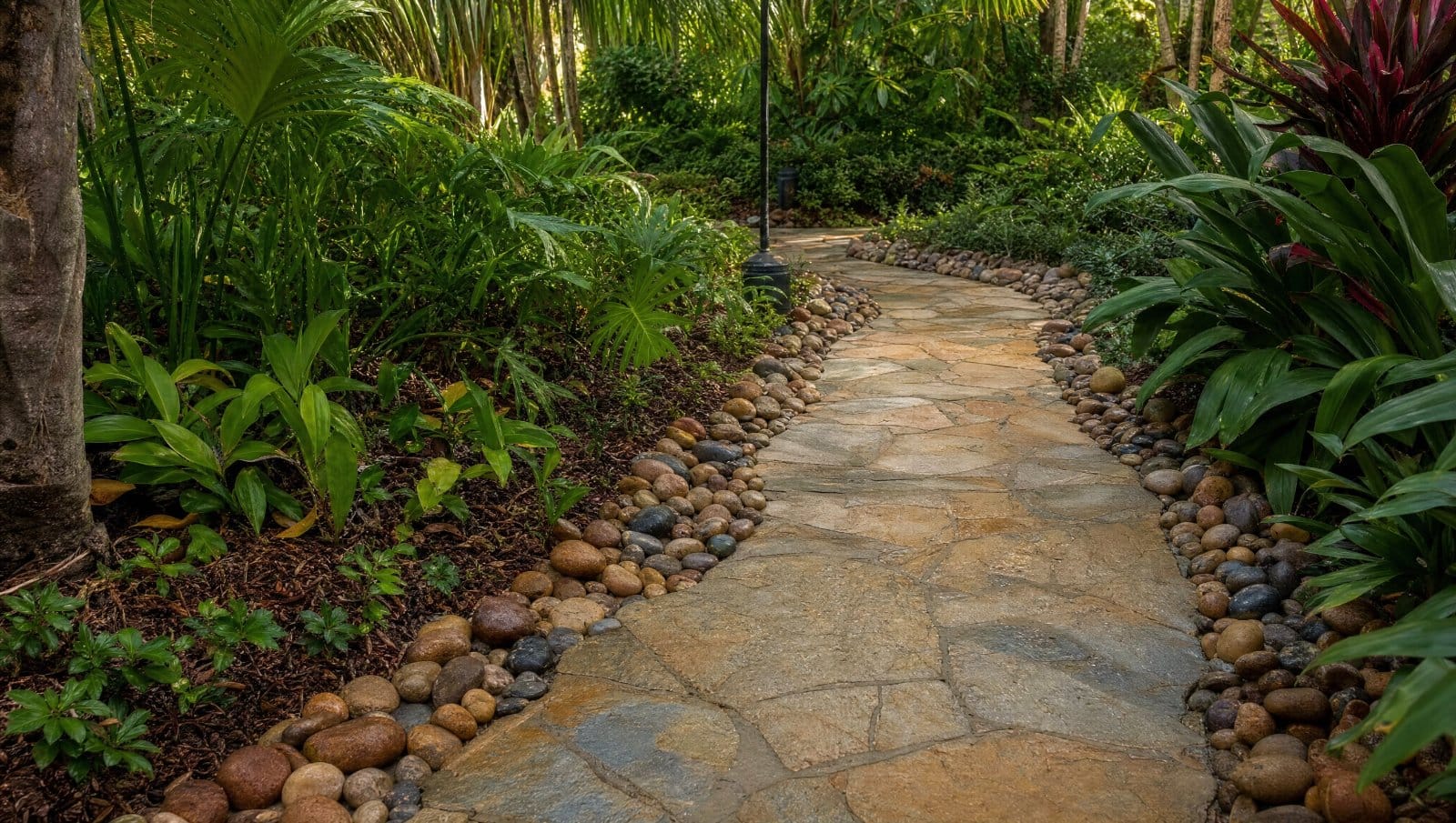 Flagstone walkway with river-rock borders and tropical plantings in a Central Florida garden