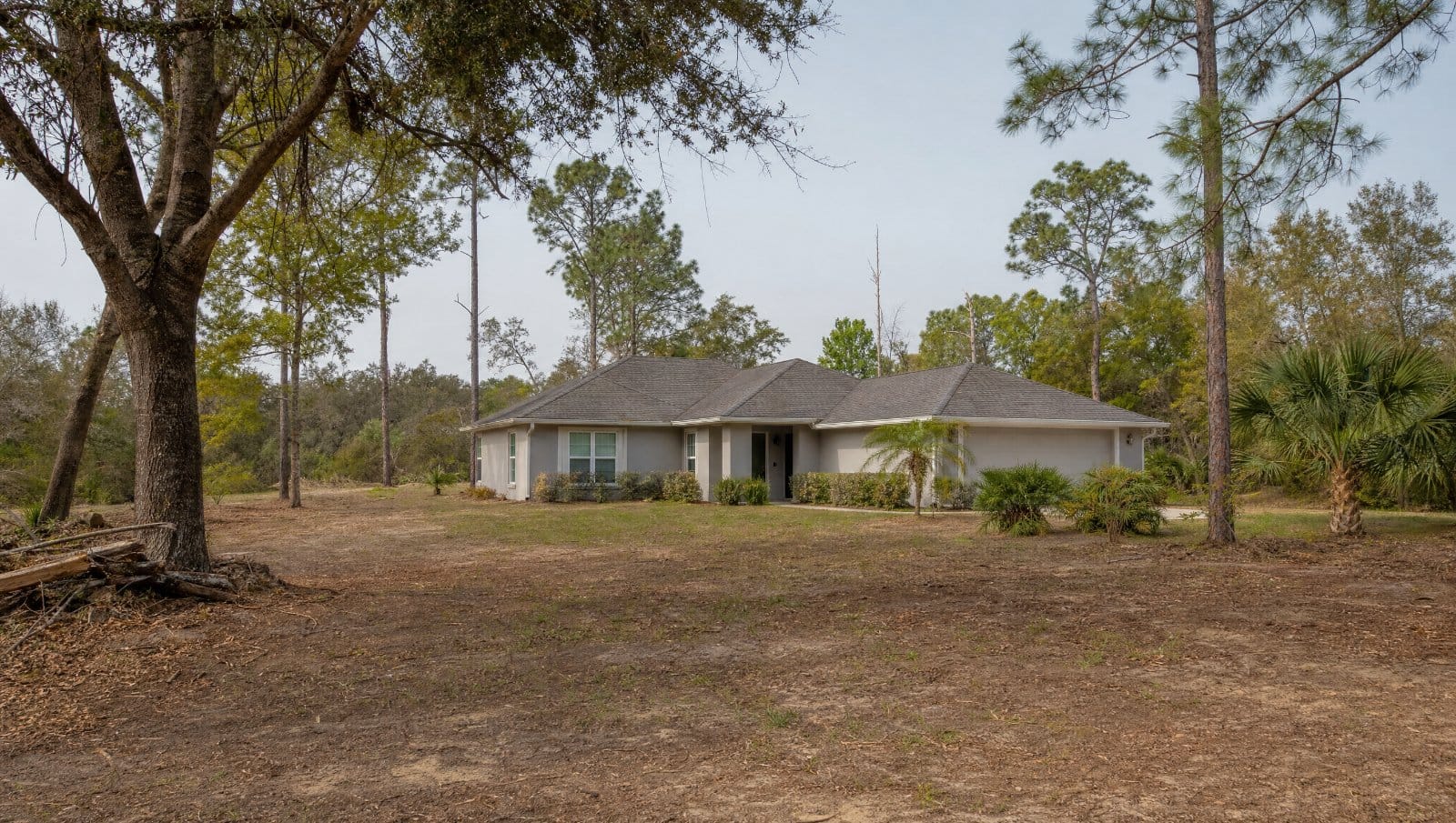 Florida home with defensible space, cleared brush and trimmed trees under a hazy sky