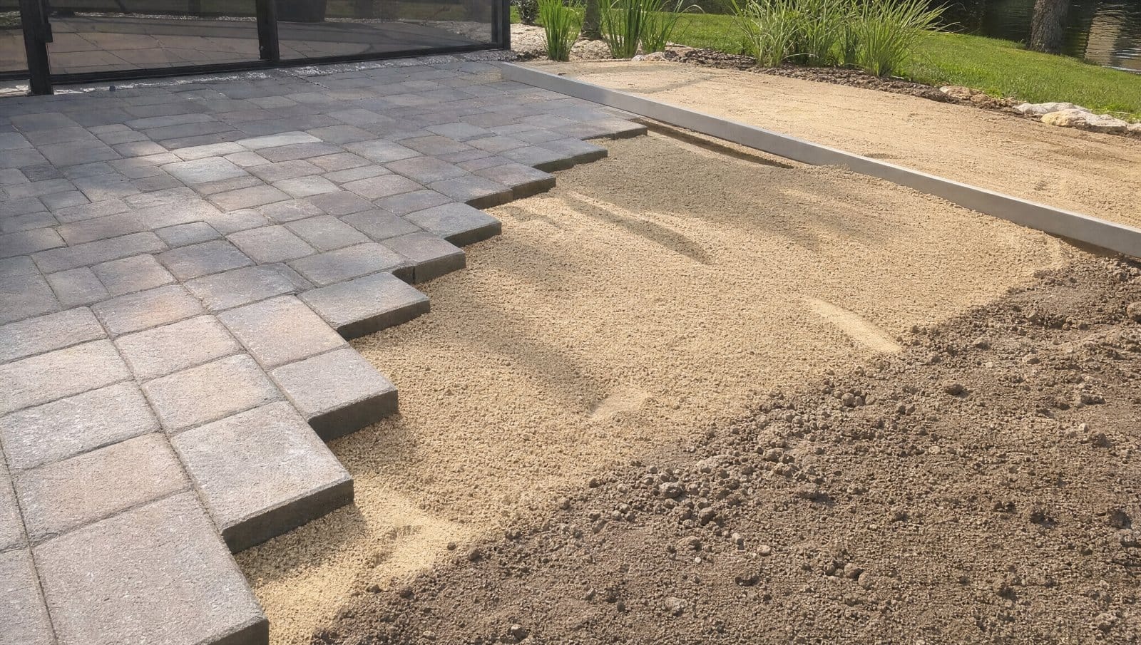 Pavers being installed over compacted dirt with a sand layer in a Florida yard