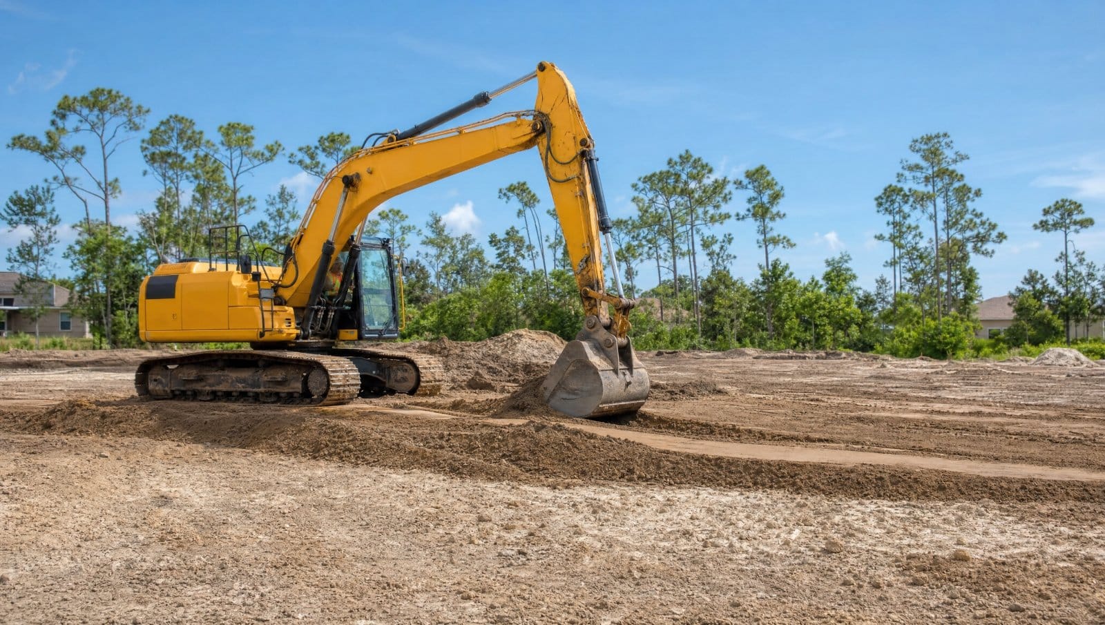 Excavator grading and shaping soil on a cleared Central Florida lot