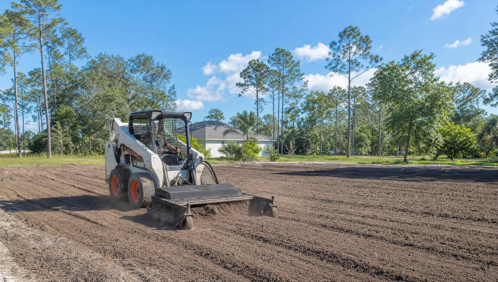 Skid steer leveling and grading bare soil on a Central Florida property