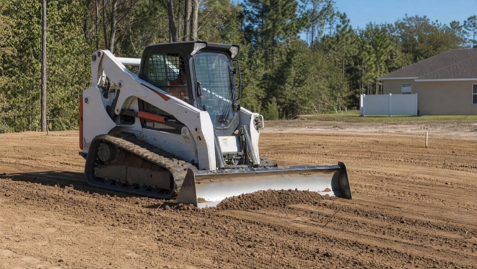 Compact track loader grading and leveling soil on a Central Florida lot