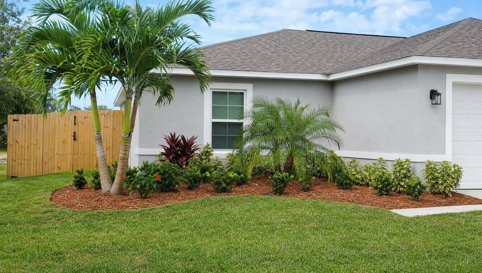 Simple tidy budget-friendly Florida landscape with mulch beds, palms and a clean lawn