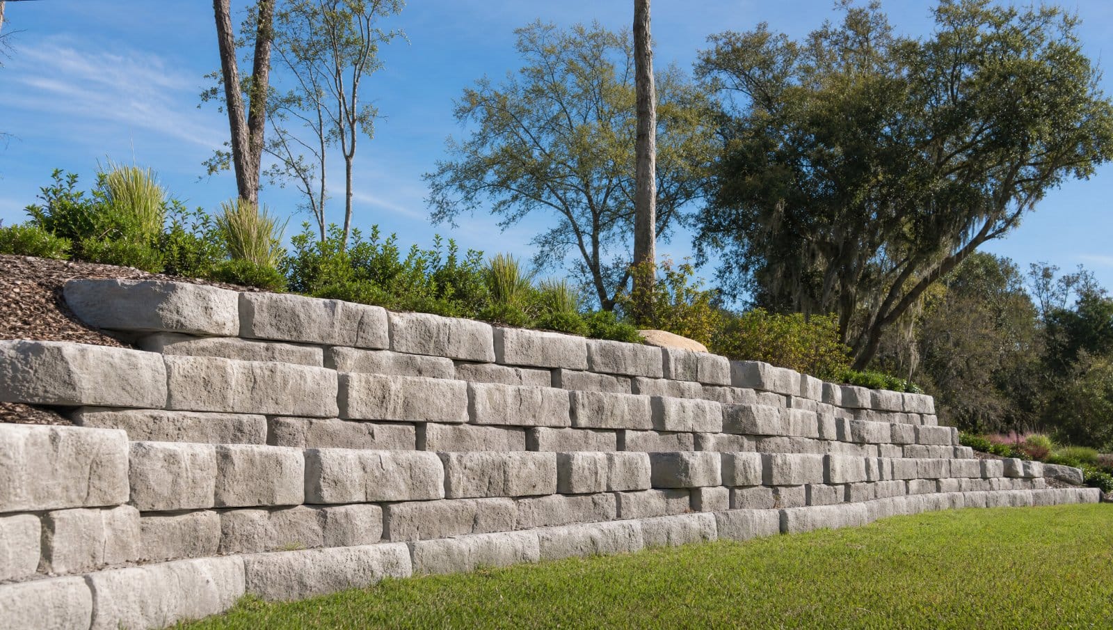 Large concrete retaining wall blocks forming a sturdy stepped wall in a Central Florida landscape