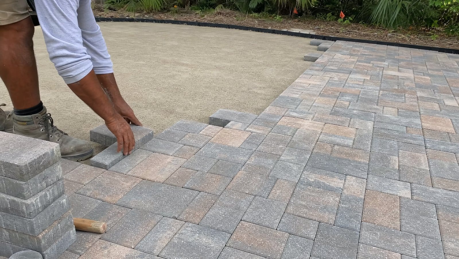 Pavers being placed over a leveled compacted surface in a Florida yard