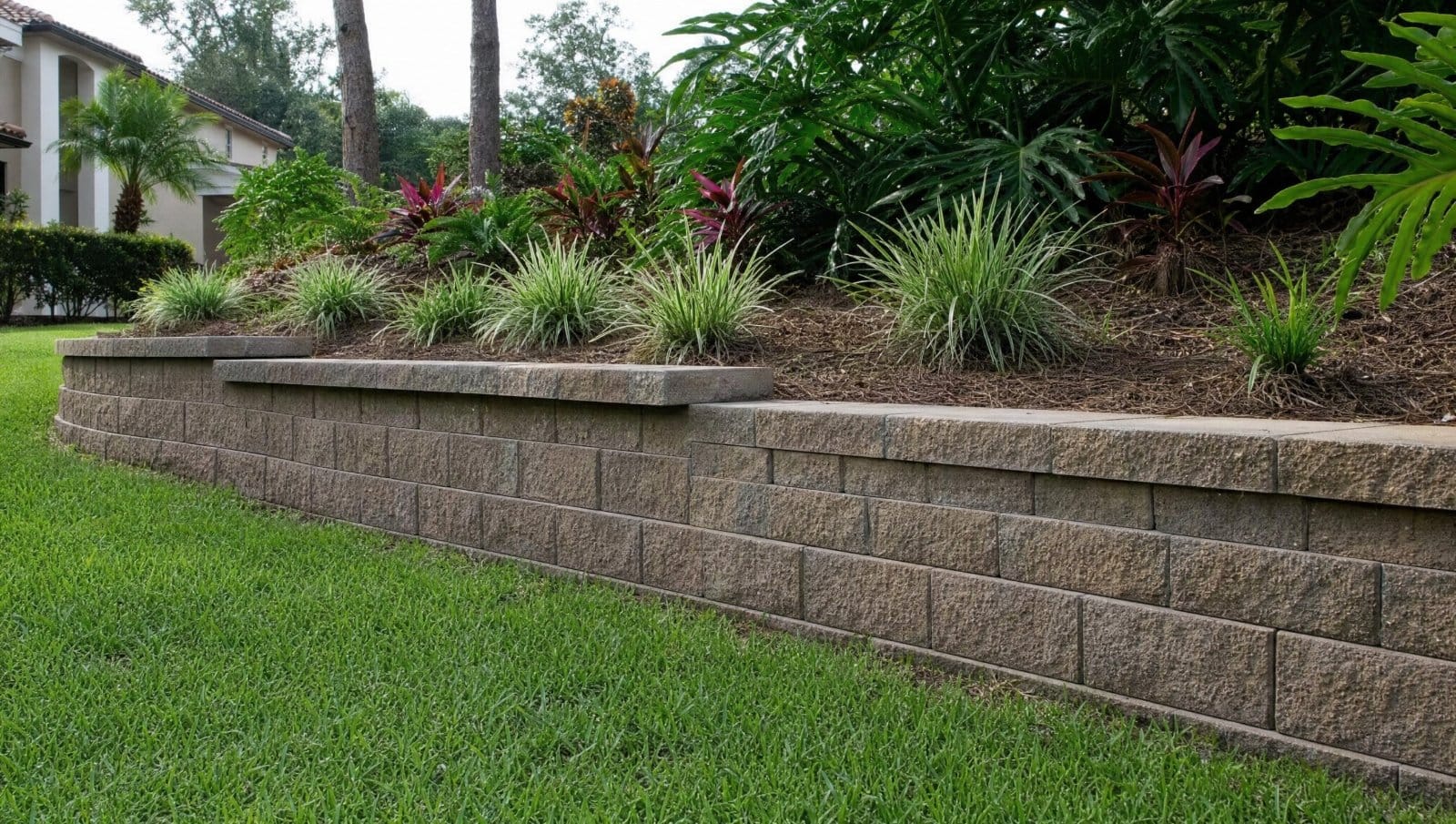 Neatly built segmental block retaining wall holding a sloped landscaped yard in Central Florida