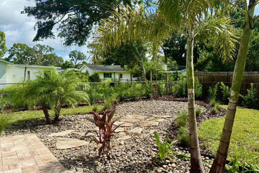 Backyard flagstone patio, river rock beds and palms designed and installed by DeAngelo's landscape contractors in Central Florida