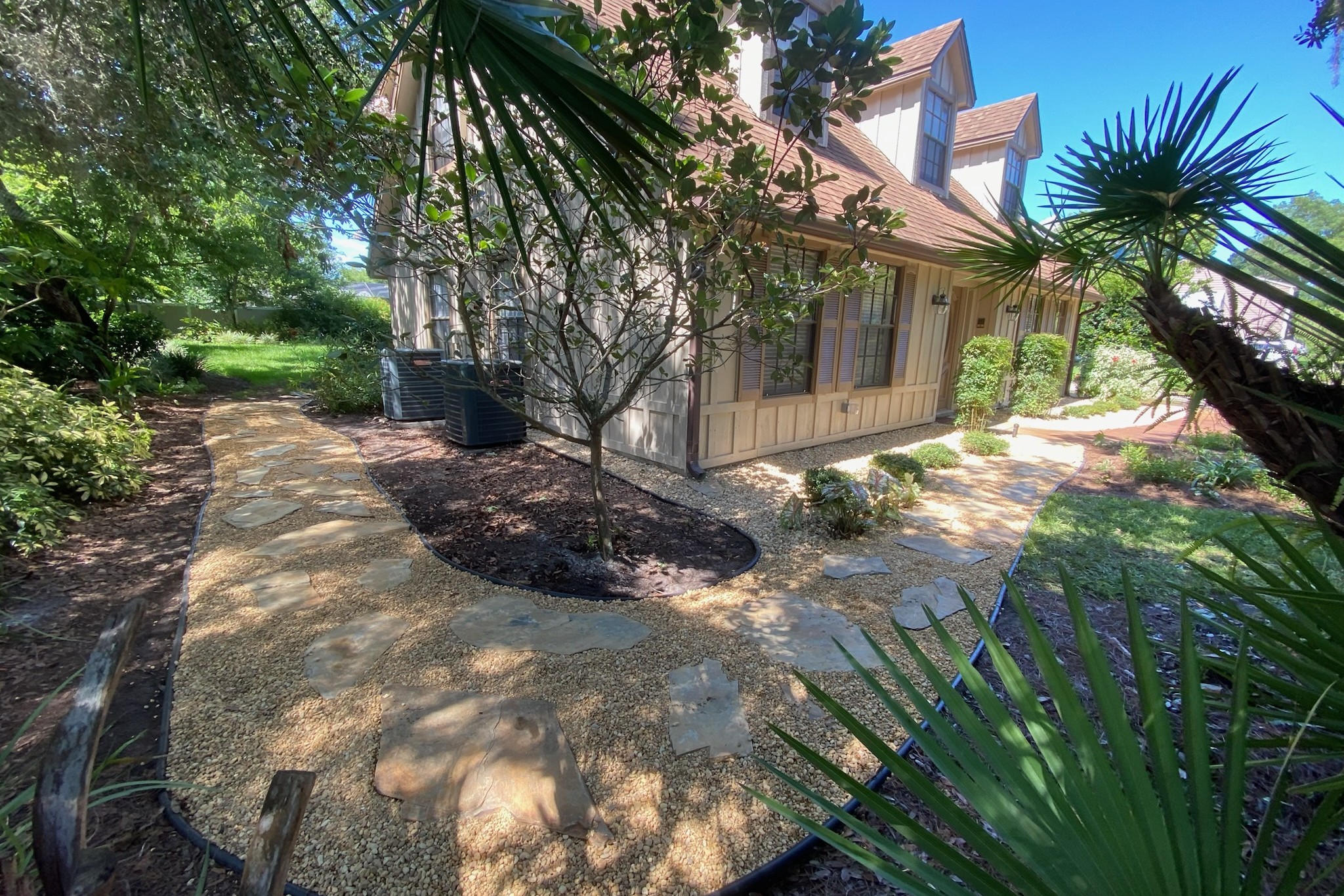 Flagstone and gravel walkway with curved planting beds at a Longwood, FL home — landscaping by DeAngelo's Land Services