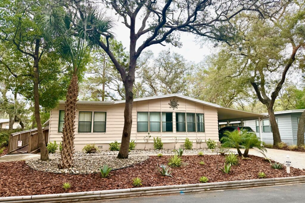 Fresh mulch beds with palms and drought-tolerant plantings across a Central Florida front yard — mulching services by DeAngelo's Land Services